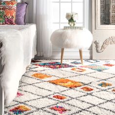 a room with a white rug and colorful pillows