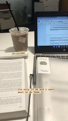 an open laptop computer sitting on top of a white desk next to a cup of coffee