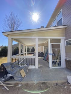 the back porch is covered with plastic sheeting and some tools are laying on the ground