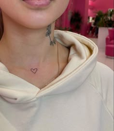 a woman with a heart and arrow tattoo on her chest is looking at the camera