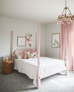 a white bed sitting in a bedroom next to a pink drapes on the window