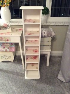 a small white desk with drawers in front of it and flowers on the window sill