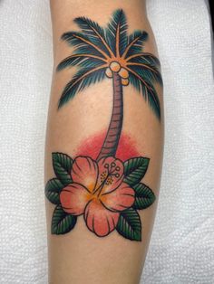 a palm tree and flower tattoo on the leg