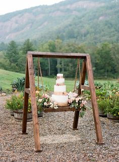 a wedding cake sitting on top of a wooden stand in the middle of a field