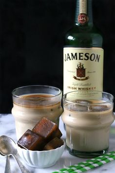 two glasses filled with ice cream next to a bottle of jameson and spoons on a table