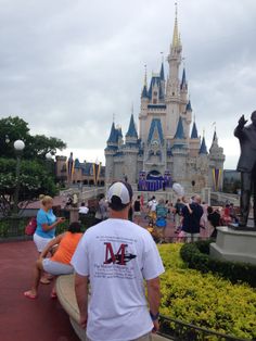 people are sitting on benches in front of the castle at disney world's magic kingdom