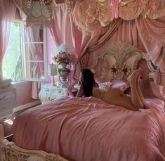 a woman laying on top of a pink bed in a bedroom