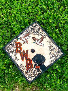 a black and white graduation cap laying on top of some green grass in the grass