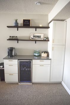 a kitchen with white cabinets and black counter tops, including a wine cooler in the corner