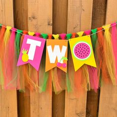 a party banner with the words twp and watermelon on it hanging from a wooden fence