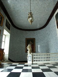 a room with a checkered floor, chandelier and painting on the wall