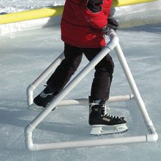 a young child is standing on an ice rink with skis and poles attached to it