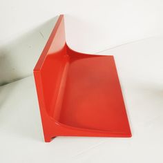 a red plastic shelf sitting on top of a white table