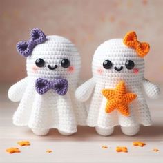 two crocheted white ghost dolls with orange bows and purple bow ties, standing next to each other