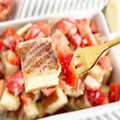 a fork holding up a piece of french toast with strawberries