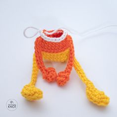 a crocheted orange and yellow hat on a white surface with a string attached to it