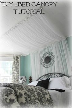 a bed with white drapes hanging from the ceiling and pillows on top of it