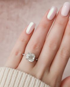 a woman's hand with a white manicured nail polish and a diamond ring