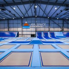 an indoor trampoline park with air space logo on the wall and blue tarps