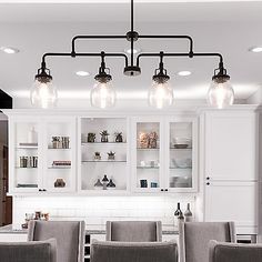 a kitchen with white cabinets and gray chairs