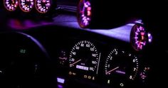 the interior of a car is lit up with red and blue lights, including gauges