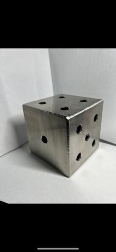 a metal object sitting on top of a white surface with holes in the center and bottom