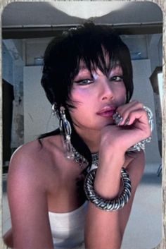 a woman with black hair and jewelry on her neck posing for a photo in front of a mirror