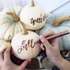 someone is writing on some pumpkins with the words welcome fall written on them in cursive letters