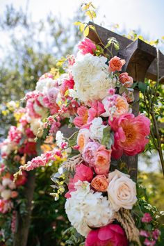 an arrangement of flowers hanging from a wooden cross