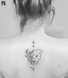 the back of a woman's neck with a deer and flowers tattoo on it