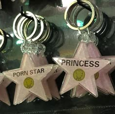 three pink star shaped key chains hanging from the side of a mirror with rings around them