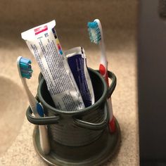 two toothbrushes in a cup on the floor