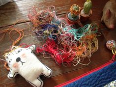 several different types of yarn on a wooden table next to stuffed animals and cacti