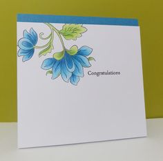 congratulations card with blue flowers and green leaves on white paper, against a yellow background