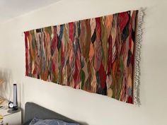 a bed with a colorful wall hanging above it