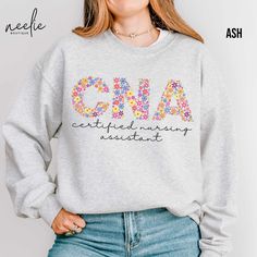 Fun and colorful floral letters spell out CNA on this cute sweatshirt for all the hardworking Certified Nursing Assistants out there!  Your coworkers and your patients will love this cozy and stylish sweatshirt designed to keep you comfortable during those long workdays while showcasing your passion for your profession.  Whether you're working hard in the hospital or spending time with friends and family, this sweatshirt will keep you warm, comfortable, and stylish.   DETAILS This classic, unise Certified Nurse Midwife, Spending Time With Friends, Doctor Of Physical Therapy, Picu Nurse, Nurse Midwife, Certified Nursing Assistant, Respiratory Therapist, Nurse Sweatshirt, In The Hospital