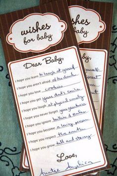 two brown and white baby shower bookmarks with handwritten wishes for babies on them