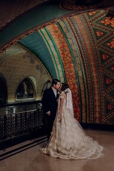 a bride and groom standing in front of a colorful wall