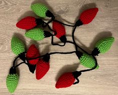 crocheted christmas lights with red and green leaves on them sitting on a wooden surface