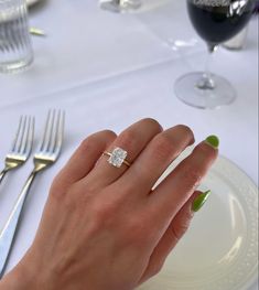 a woman's hand with a ring on top of her finger next to a plate