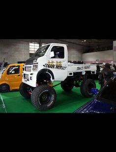 a white truck parked next to other trucks on display at a car show in a building