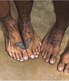 two people with tattoos on their feet standing next to each other