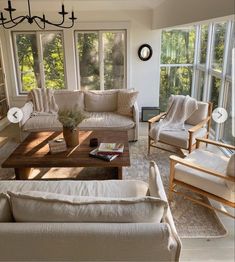 a living room with couches, chairs and coffee table in front of large windows