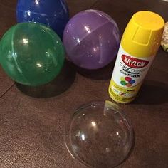 three plastic balls, one yellow and one green are sitting on the floor next to an empty cup