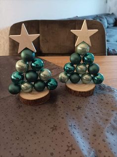 two christmas trees made out of wood with green balls and silver stars on the top