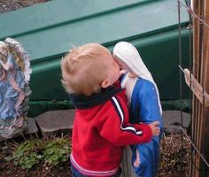 two small children standing next to each other in front of a fence with statues behind them