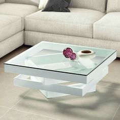 a glass coffee table sitting on top of a tile floor next to a white couch