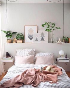 an unmade bed in a bedroom with plants on the wall and pictures above it