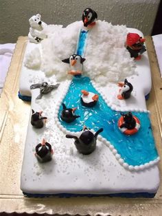 a birthday cake with penguins on it and water in the middle that is made out of icing