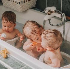 three babies are playing in the bathtub together